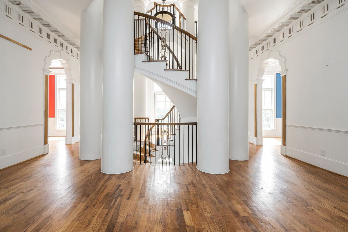 A room with several huge white columns around a spiral staircase. 