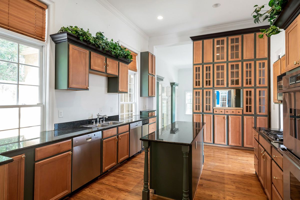 A huge kitchen with wooden cabinets and a few columns. 