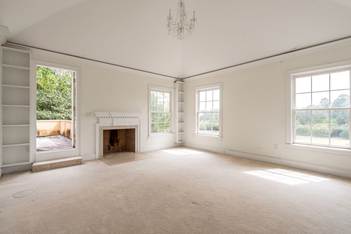 A huge white master bedroom with a chandelier on the ceiling. 