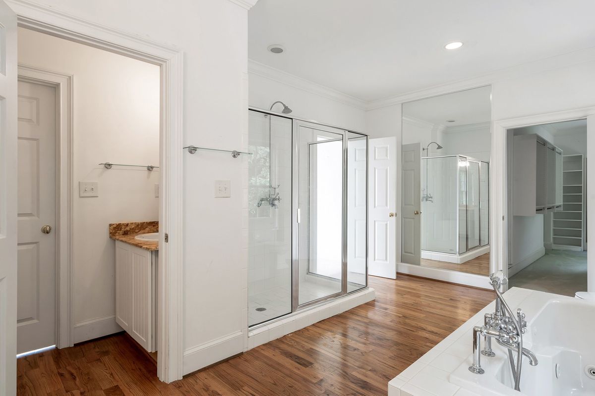 A huge white master bathroom with a large mirror.