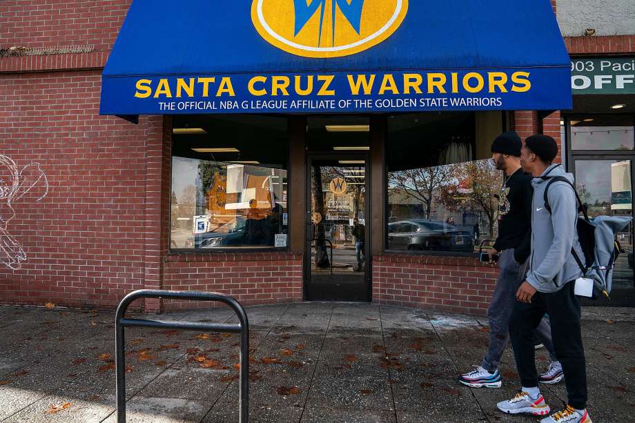 Santa Cruz Warriors guard Vander Blue, center right, walks with Warriors Basketball Operations and Team Player Development manager Mike Newton, right, past the Santa Cruz Warriors storefront. Photo: LiPo Ching / Special To The Chronicle