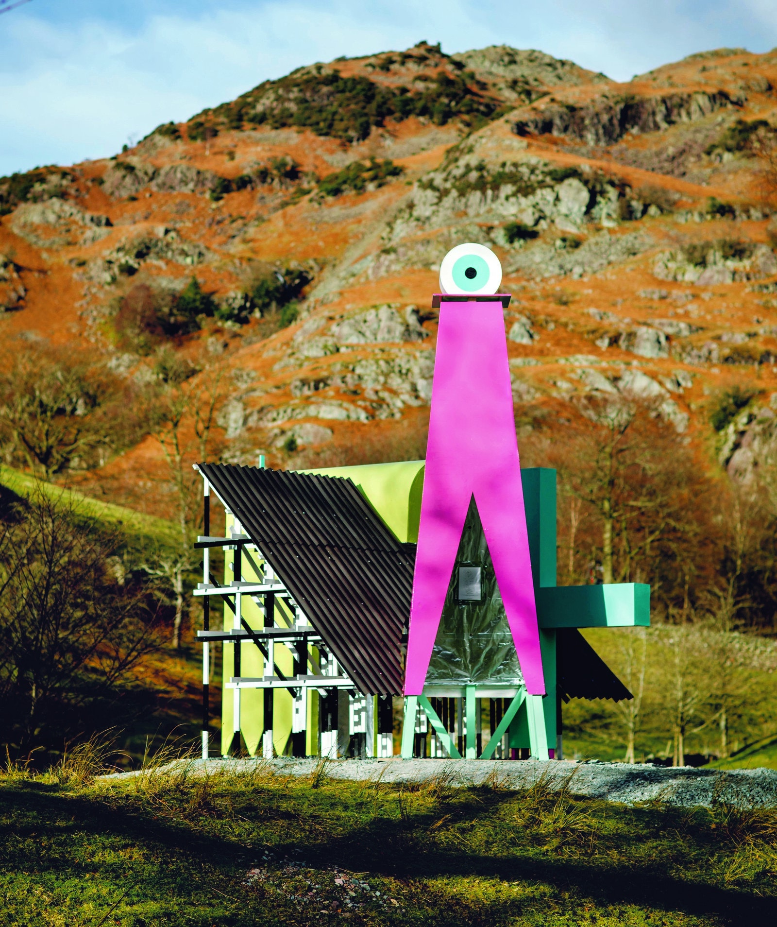 a slanted house with a giant pink sculpture and an eyeball