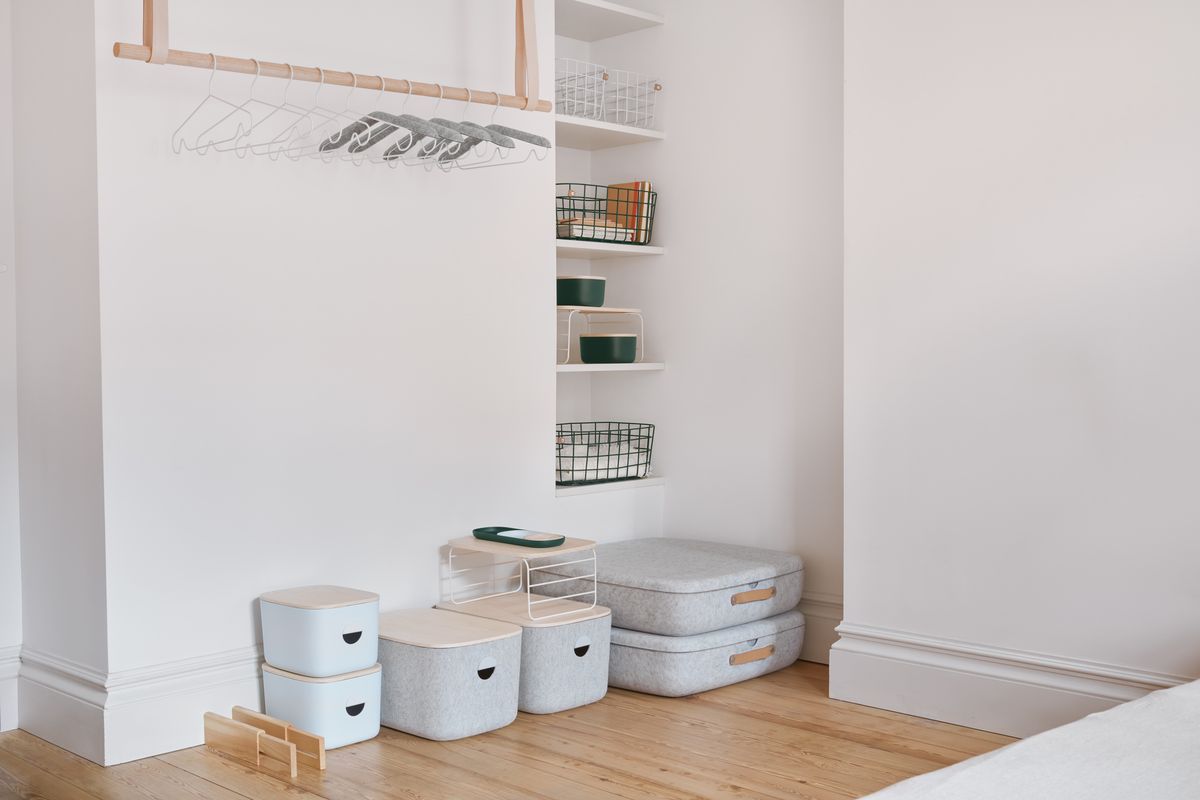 Rounded bins in gray and pale wood lined up against wall.