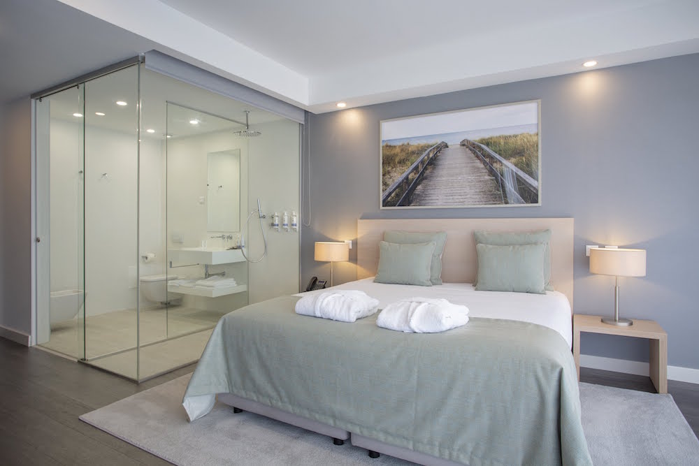 Luxe, clean and simple hotel bed with glass bathroom