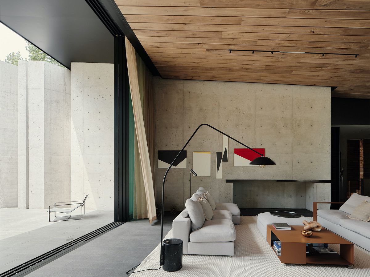 Living room featuring concrete walls and timber paneled ceiling.
