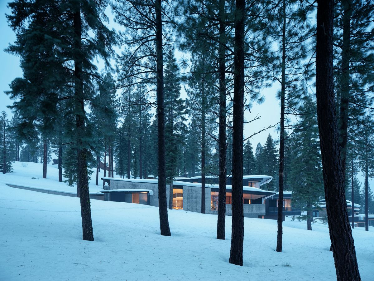 House on a snowy slope surrounded by trees.
