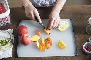 a person cutting food on a table: OXO double sided cutting board