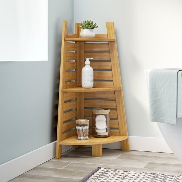 A triangular shelf with three small storage spaces, all open and visible. It is made of bamboo. 