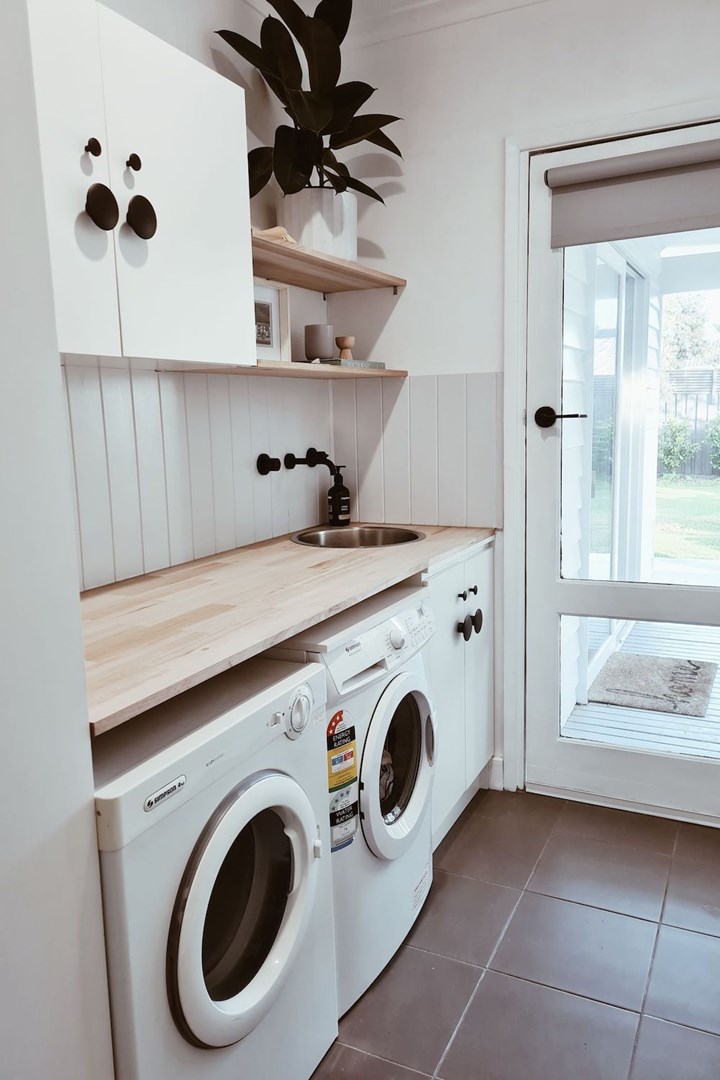 Renovated laundry with timber bench, plant and photographs