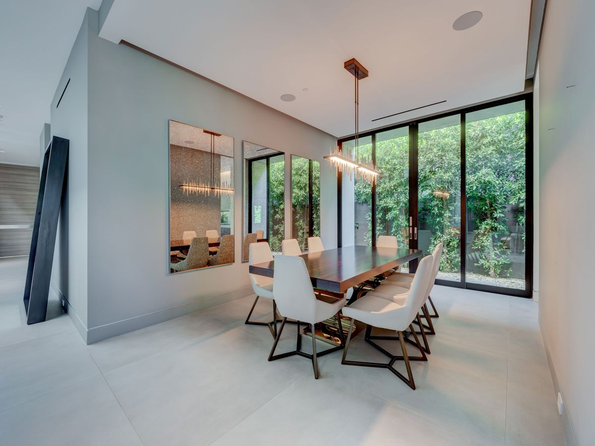 A dining room with a dining set and floor-to-ceiling windows overlooking greenery. 