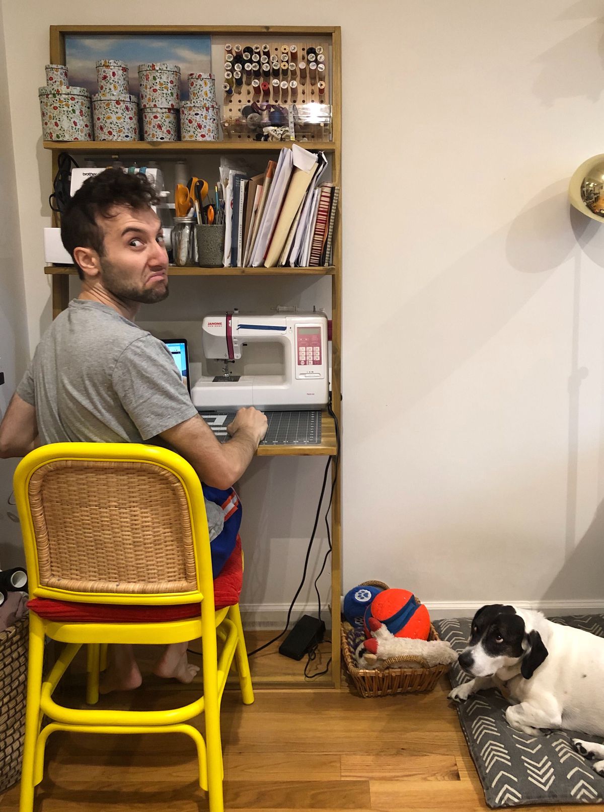 Seth working at his wife’s sewing desk while dog Trudy looks on