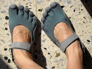 a close up of feet wearing blue shoes: A pair of Vibram Five Finger minimalist shoes. Wikimedia Commons