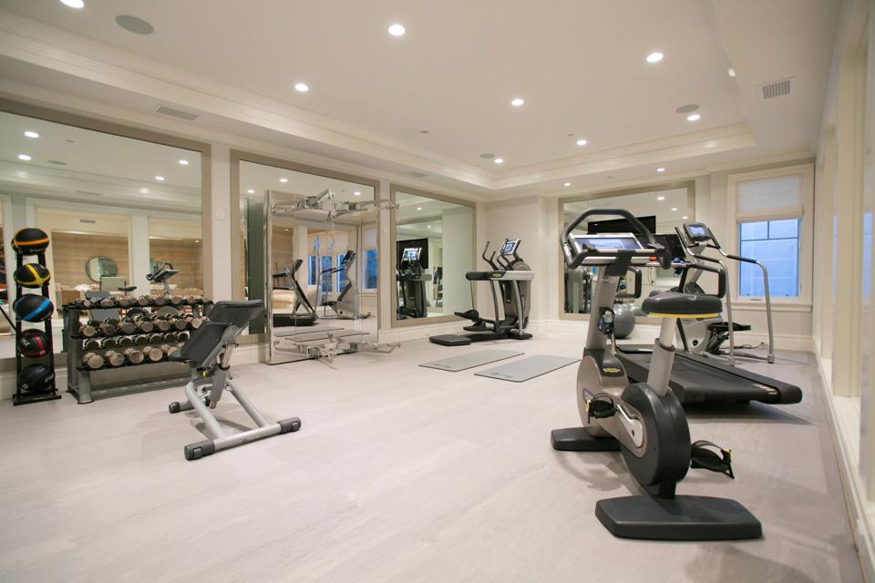 A home gym with light flooring, recessed lighting and white walls.